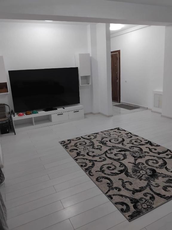 a living room with a flat screen tv and a rug at Apartament Militari in Chiajna