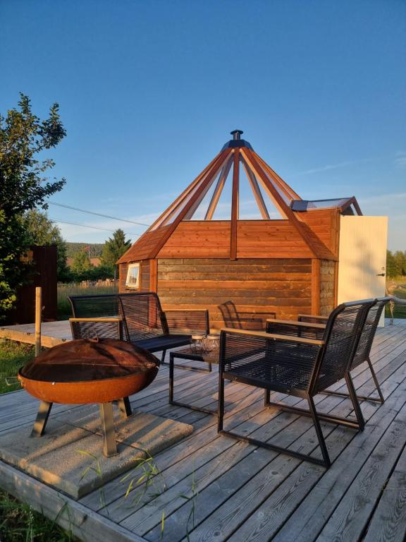 a wooden deck with chairs and a gazebo at Lavvo med glasstak in Svenseid