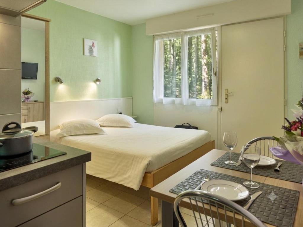 a bedroom with a bed and a table with chairs at Hôtel Résidence Les Grands Chênes Amnéville les Thermes in Amnéville