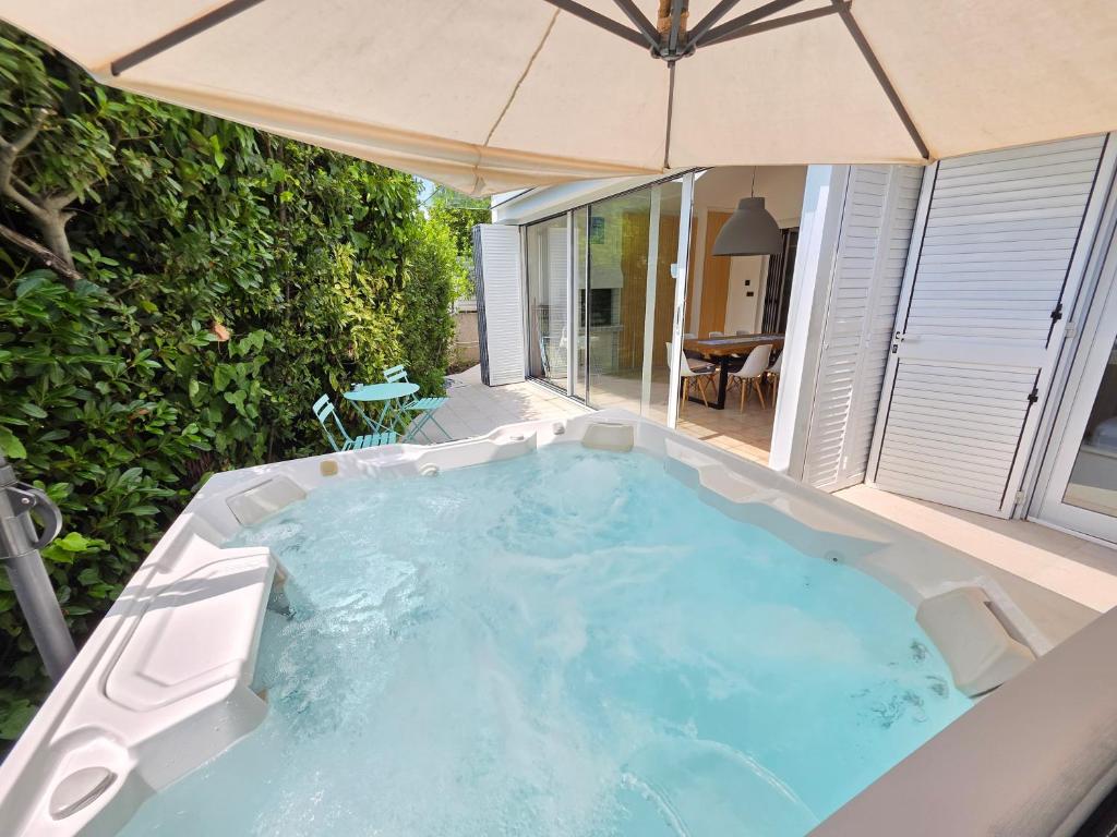 a hot tub in a backyard with an umbrella at Villa Dvojac Holiday house with Jacuzzi and grill in Jadranovo
