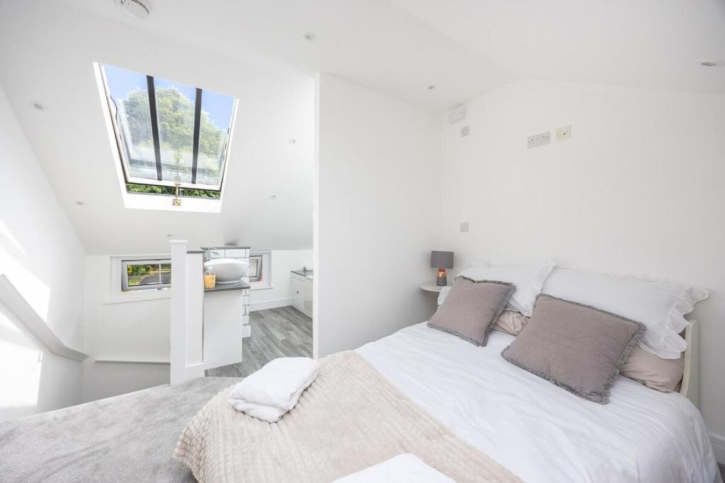 a white bedroom with a large bed and windows at Stylish 2BR Cottage in Chesham in Chesham