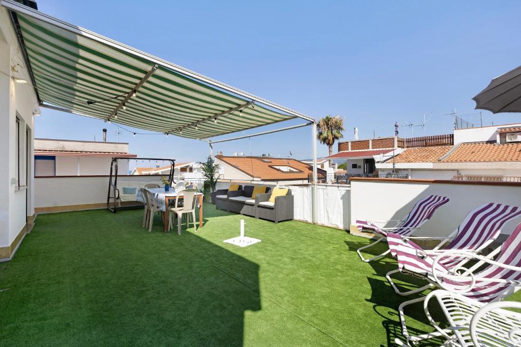 a patio with green grass and chairs on a balcony at A due passi dal mare in Oliveri