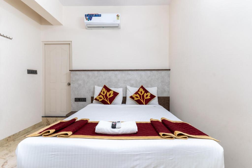 a bedroom with a large white bed with red and yellow pillows at Hotel metro grand in Bangalore
