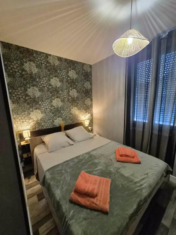a bedroom with a bed with two orange towels on it at Petunia in Commentry