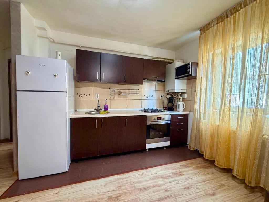 a kitchen with a white refrigerator and wooden cabinets at Stejarului Apartment in Floreşti