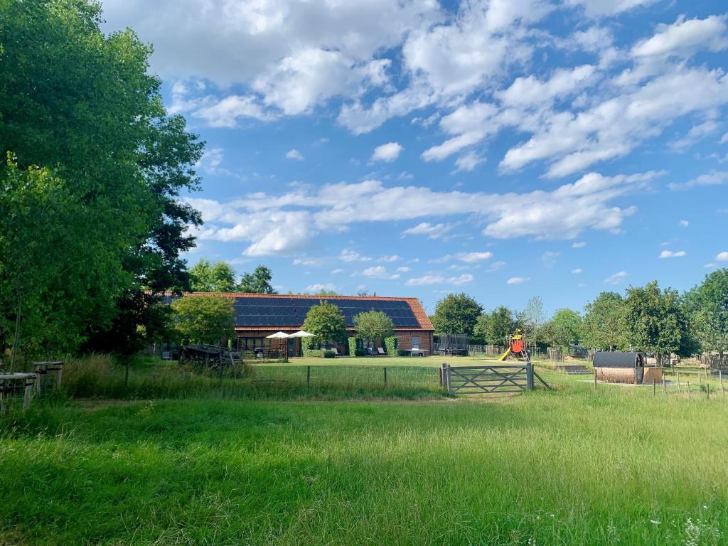 a barn in a field with a fence and green grass at Landgoed Palingbeek B&B in Ieper