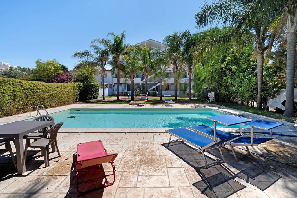 a swimming pool with two chairs and a table and a table and chairs at Casa Marea in Marzamemi