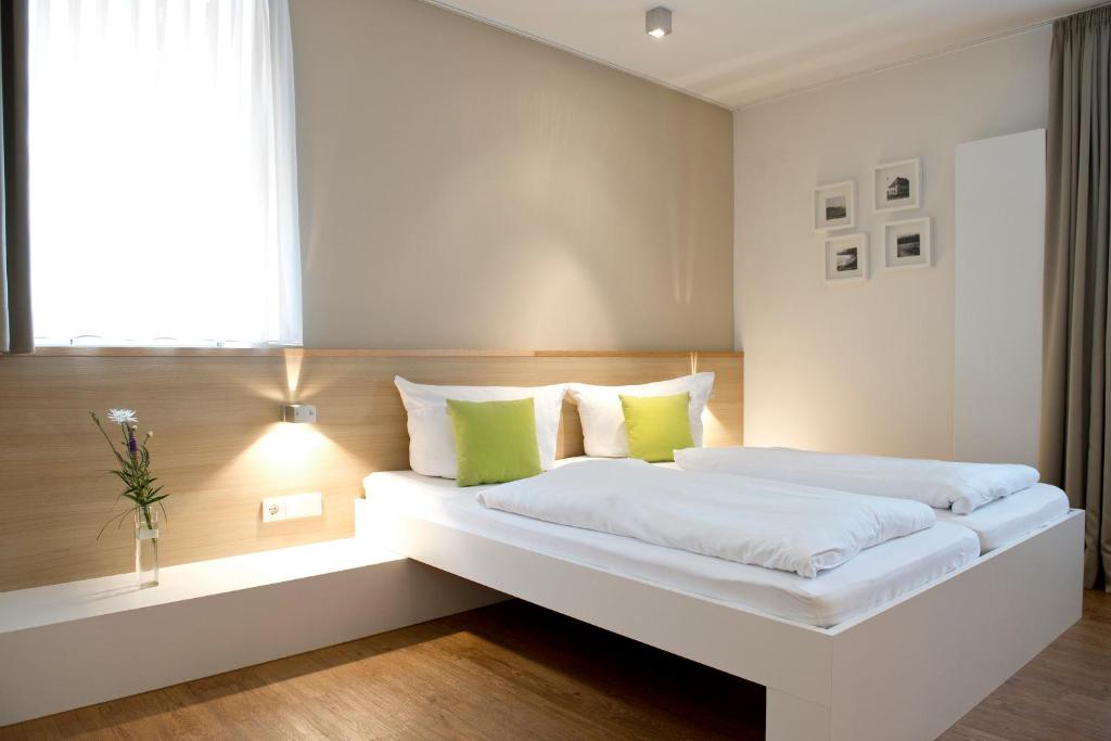 um quarto com uma grande cama branca com almofadas verdes em Volkspark em Bamberg