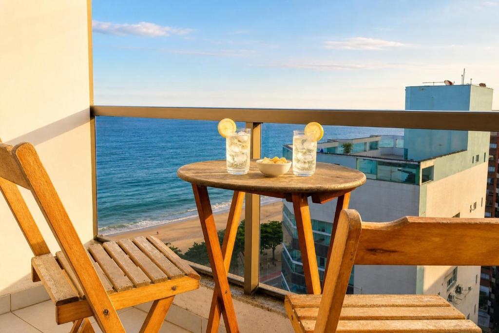 a table and chair on a balcony with a view of the ocean at Praia Dourada SUÍTE ITAPARICA 1206 in Vila Velha