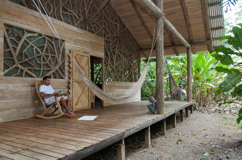 a woman sitting in a hammock on a porch of a house at Danta Corcovado Lodge in Rincón