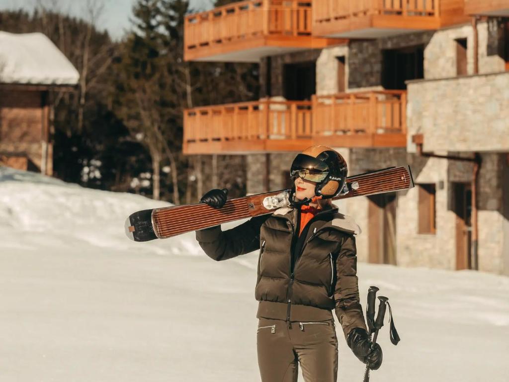 a woman holding a pair of skis on her face at Barma Résidence & Appartements in Courchevel