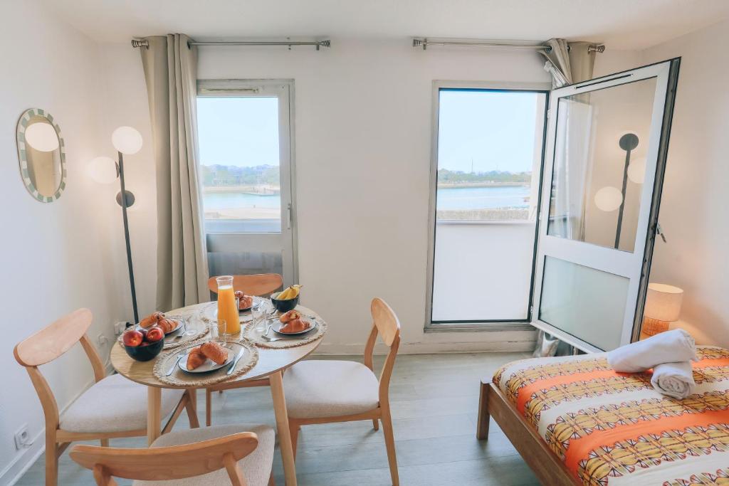 a room with a table and chairs and a bed at Vue mer, sur le port, près des tours in La Rochelle