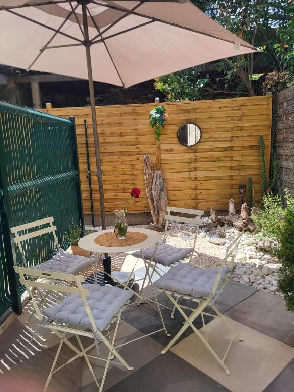 a patio with a table and chairs and an umbrella at Paisible T2 climatisé avec jardinet in Béziers