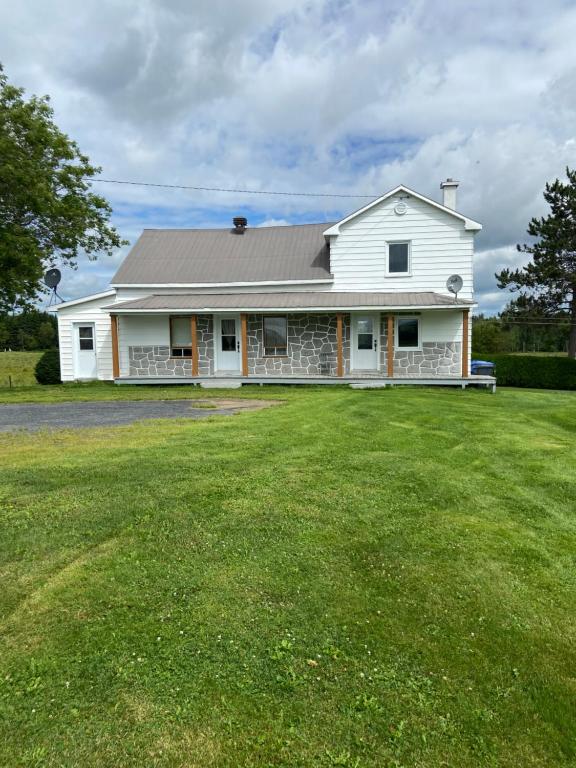 a white house with a large grass yard at maison chez René in Saint-Malachie