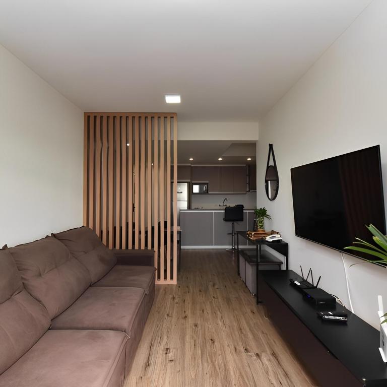 a living room with a couch and a flat screen tv at Apart 1803 - Centro Curitiba in Curitiba