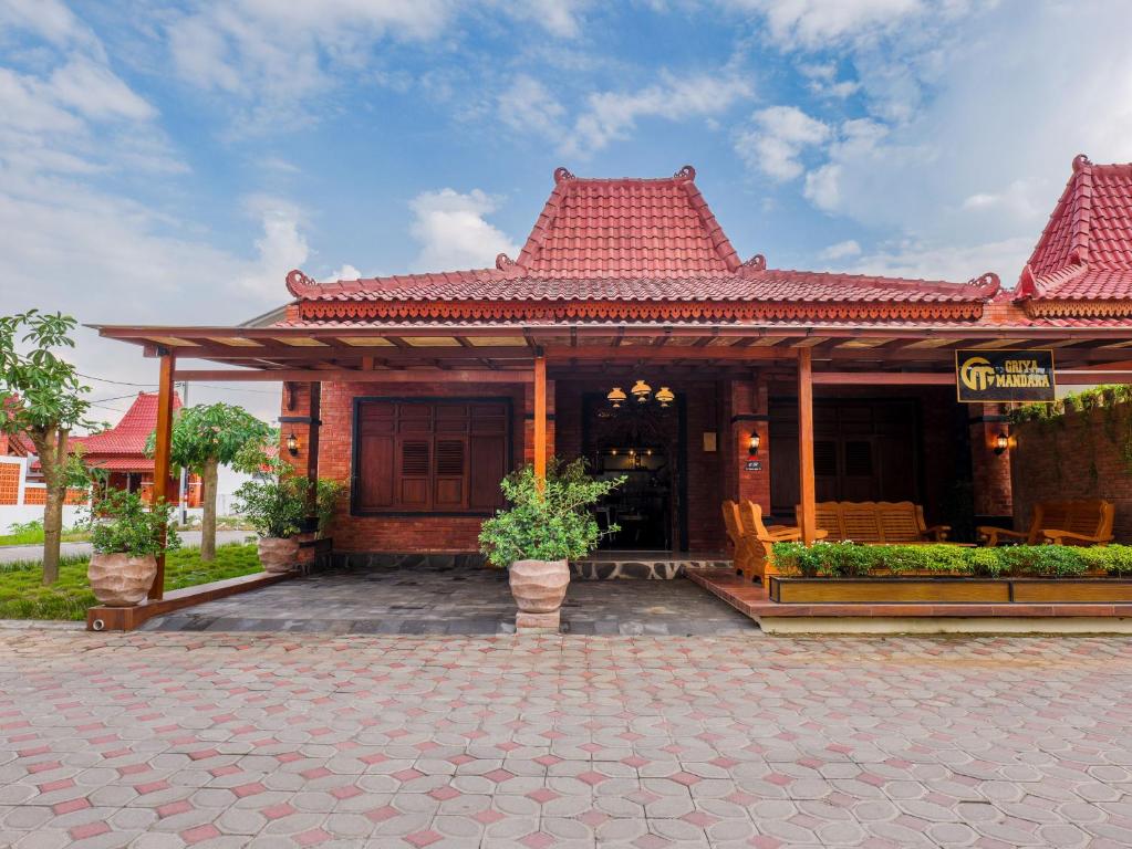 a building with a red roof and a patio at Griya Mandara Homestay Prambanan in Bugisan