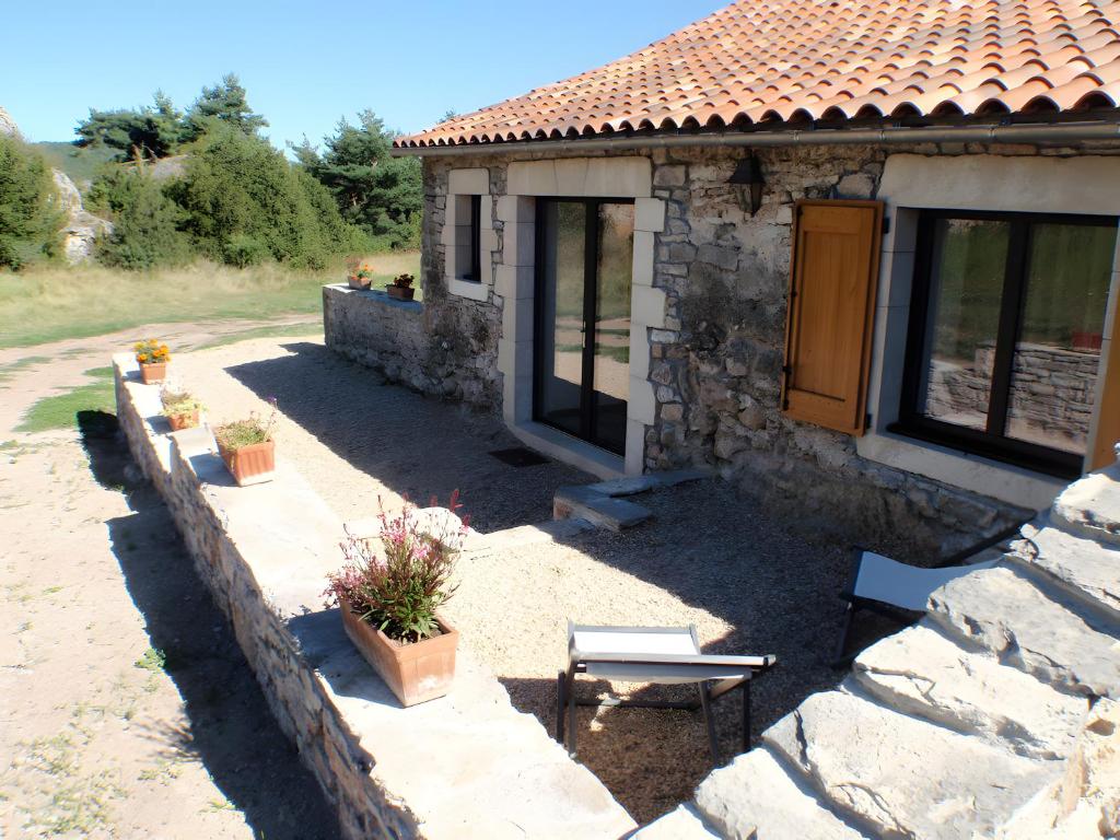 a stone house with a table and a bench outside at Domaine De Jassenove in Millau