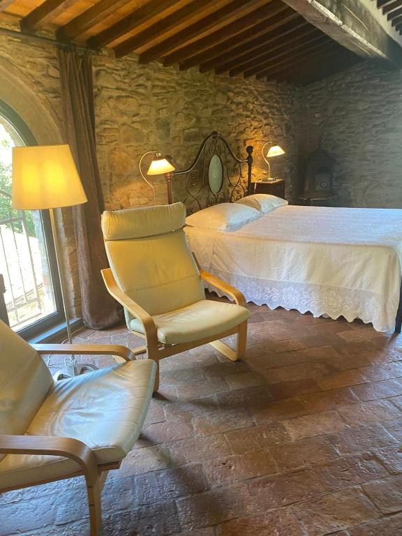 a bedroom with a bed and chairs in a room at il MOLENDINO in Calci
