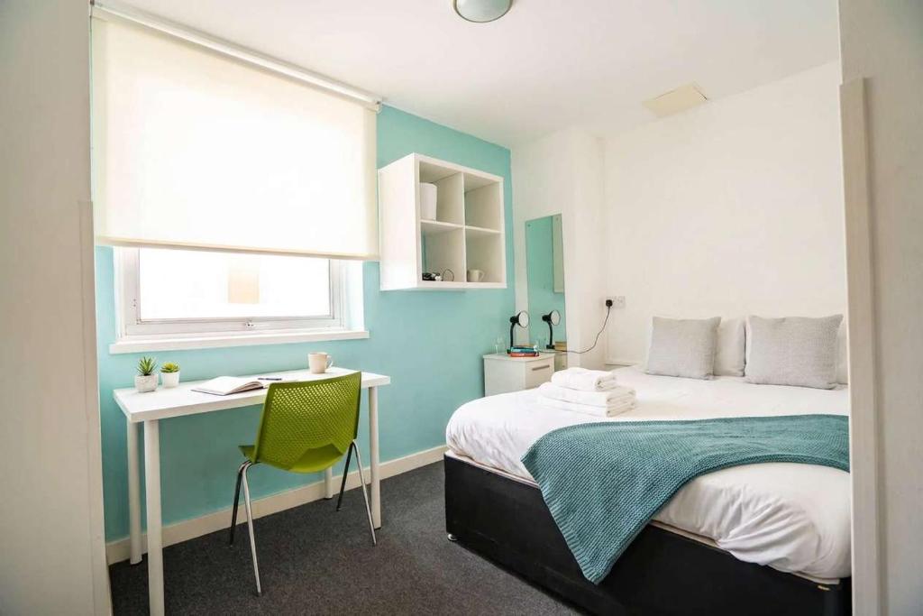 a bedroom with a bed and a desk and a window at Budget En-suite Room in Coventry City Centre in Coventry