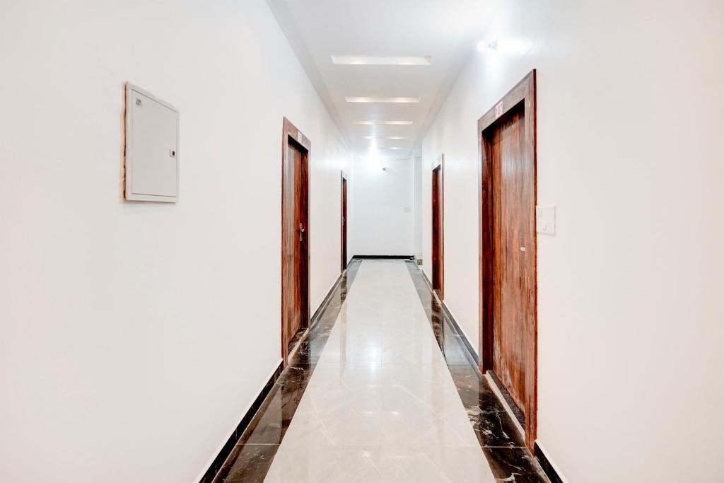 a corridor of white walls with wooden doors at HOTEL O SAMRAT INN in Prayagraj