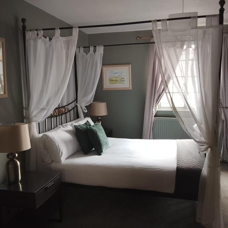 a bedroom with a large white bed with curtains at Smugglers Hotel in Brixham