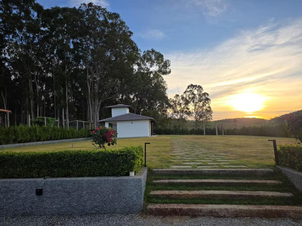 a sunset in a field with a building in the distance at Nosso Loft Sebollas - 4C in Paraíba do Sul