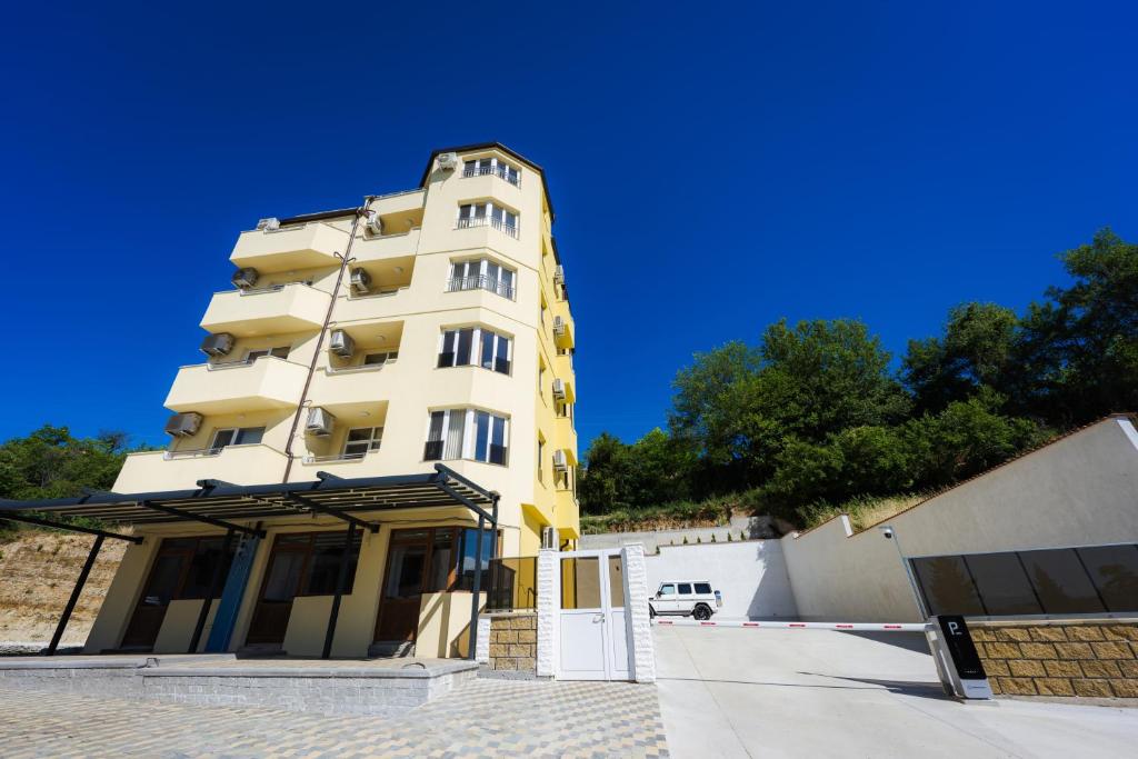 a tall yellow building with a car parked next to it at Къща за гости Вихрен-Сандански in Sandanski