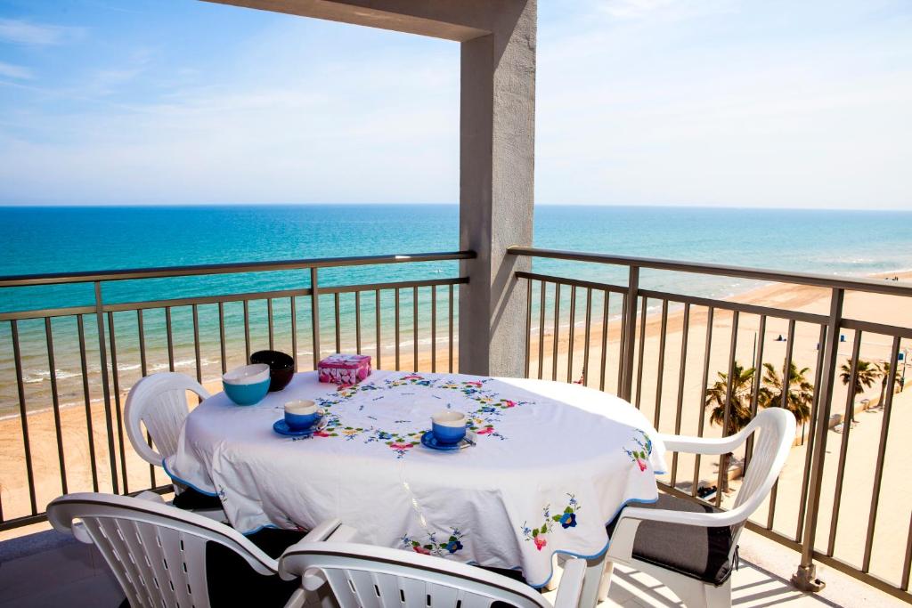 a table on a balcony with a view of the beach at Apartamentos Guillem in Playa de Miramar