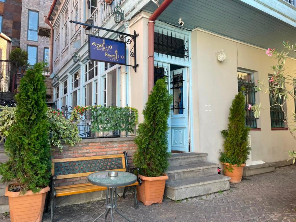 a bench in front of a building with a table at Hostel Room 110 in Tbilisi City