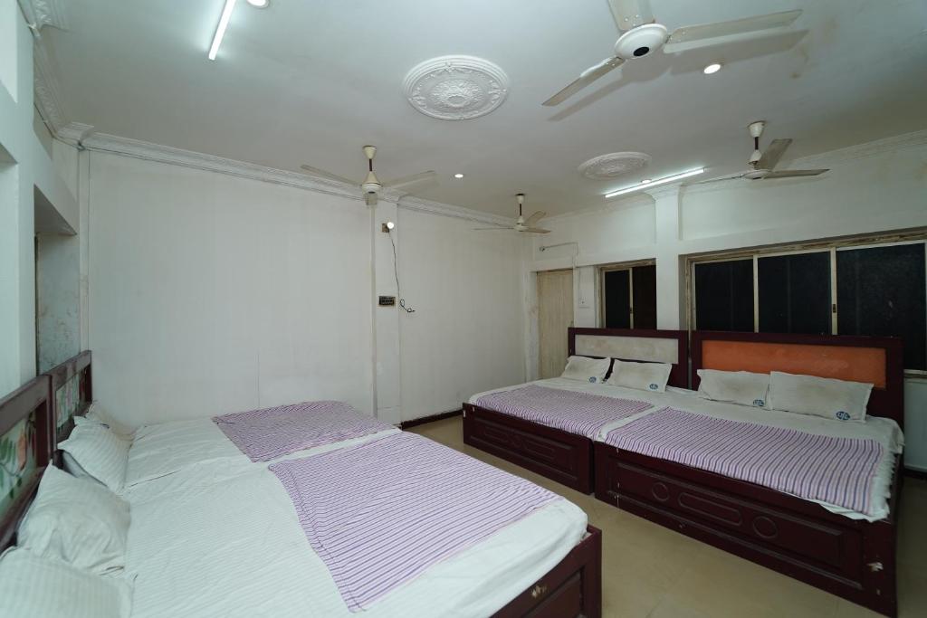 two beds in a room with purple and white sheets at Udhaya Lodge in Rāmeswaram