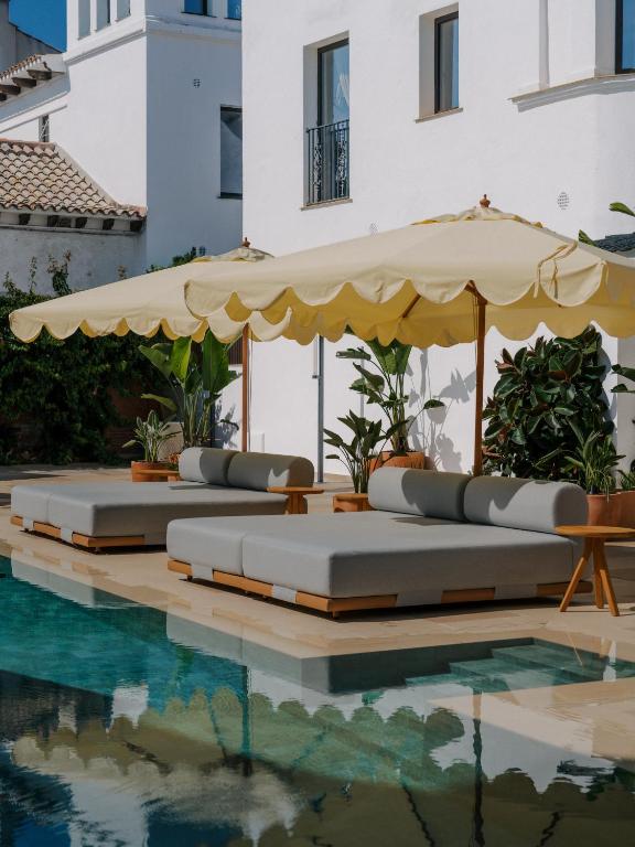 eine Reihe von Liegestühlen mit Sonnenschirm und ein Pool in der Unterkunft CASA METT Sitges - Fully refurbished in Sitges