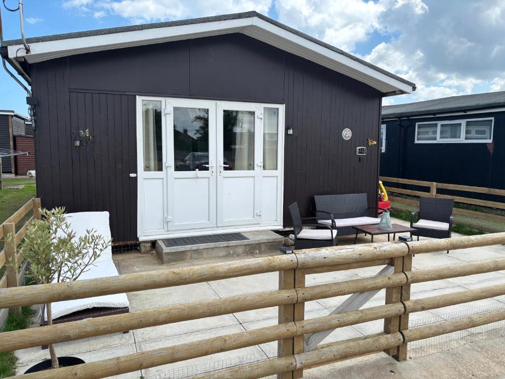 a black house with two chairs and a fence at Retreat to the Chalet in Withernsea