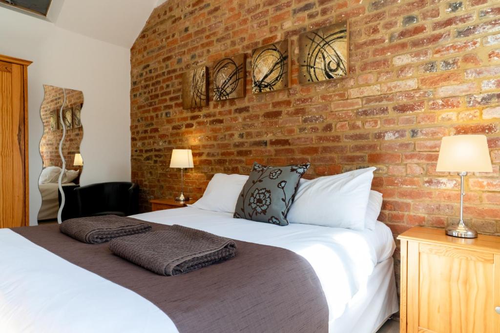 a bedroom with a brick wall and a bed at Tove Valley Cottages in Towcester