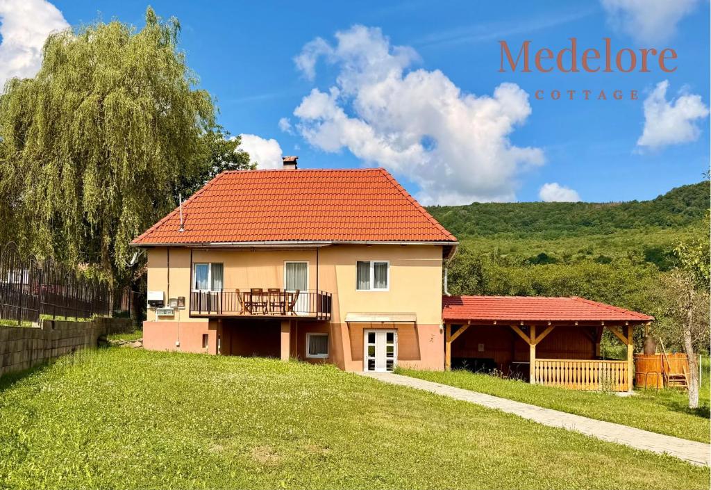 a house with an orange roof and a yard at Medelore Cottage in Medişoru Mare