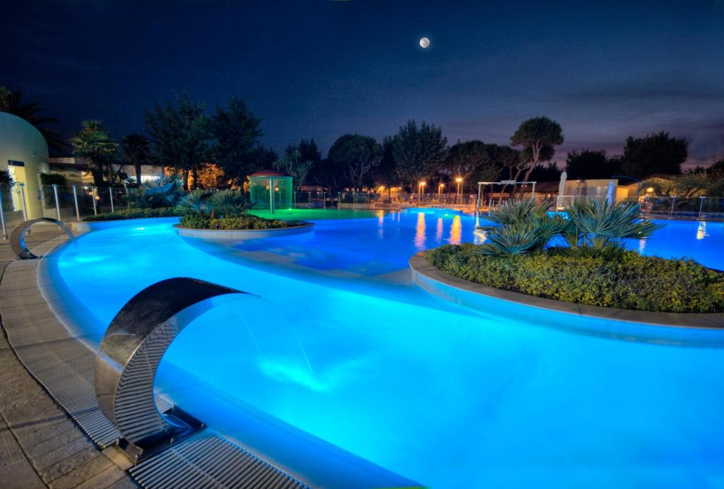 uma piscina com iluminação azul à noite em Numanablu Island - Family & Sport Resort 4 stelle em Numana