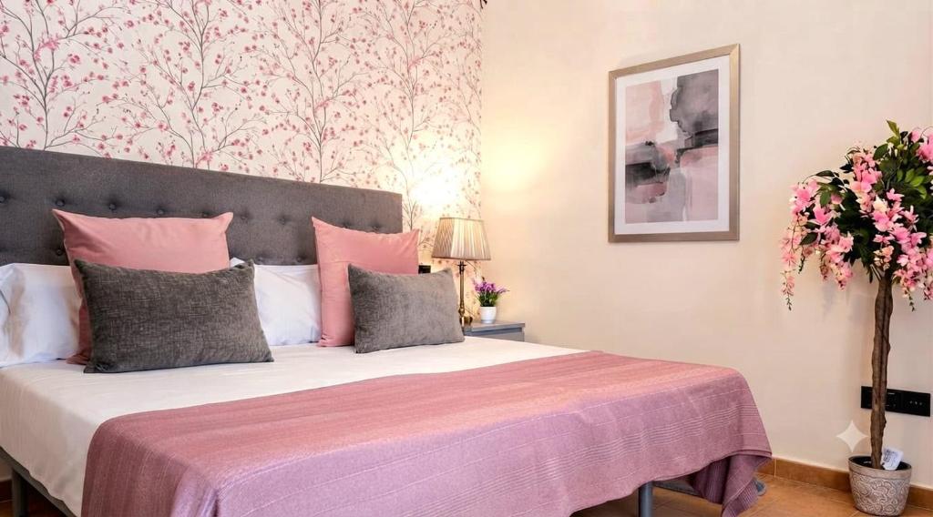 a bedroom with a bed with pink and grey pillows at Alquilaeasy Marbella Views Ojen in Ojén