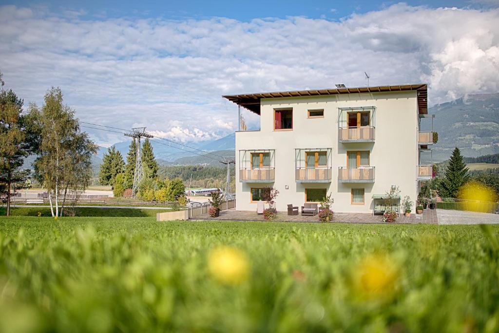 a white building with a green field in front of it at B&B Garni Schorneck in Brunico