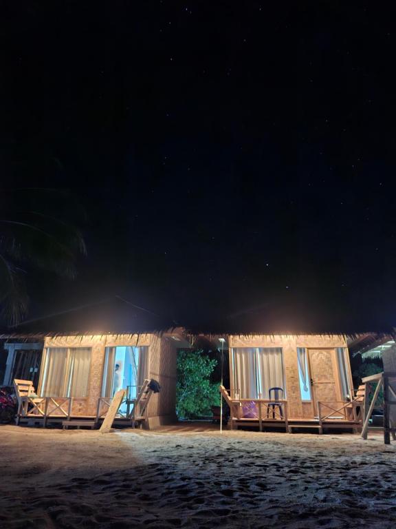 a cabin on the beach at night with lights at Batu Mela Cottage in Banggai