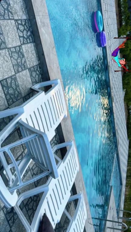 a group of white chairs next to a swimming pool at Sunset Garden Apartment 3 in Bilgah