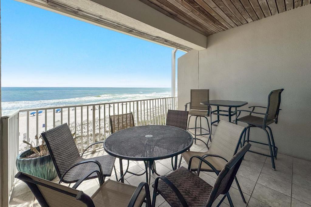 a balcony with tables and chairs and the ocean at Dolphin Key 3C in Orange Beach
