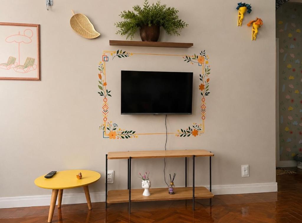 a living room with a tv on a wall at Apartamento Charme da Glória in Rio de Janeiro