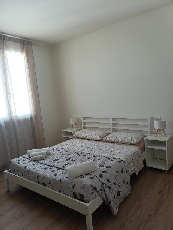a white bedroom with a bed and two windows at B&B Rita in Due Maestà