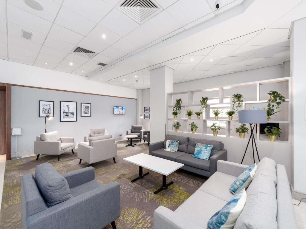 a waiting room with couches and chairs and a table at Novotel Southampton in Southampton