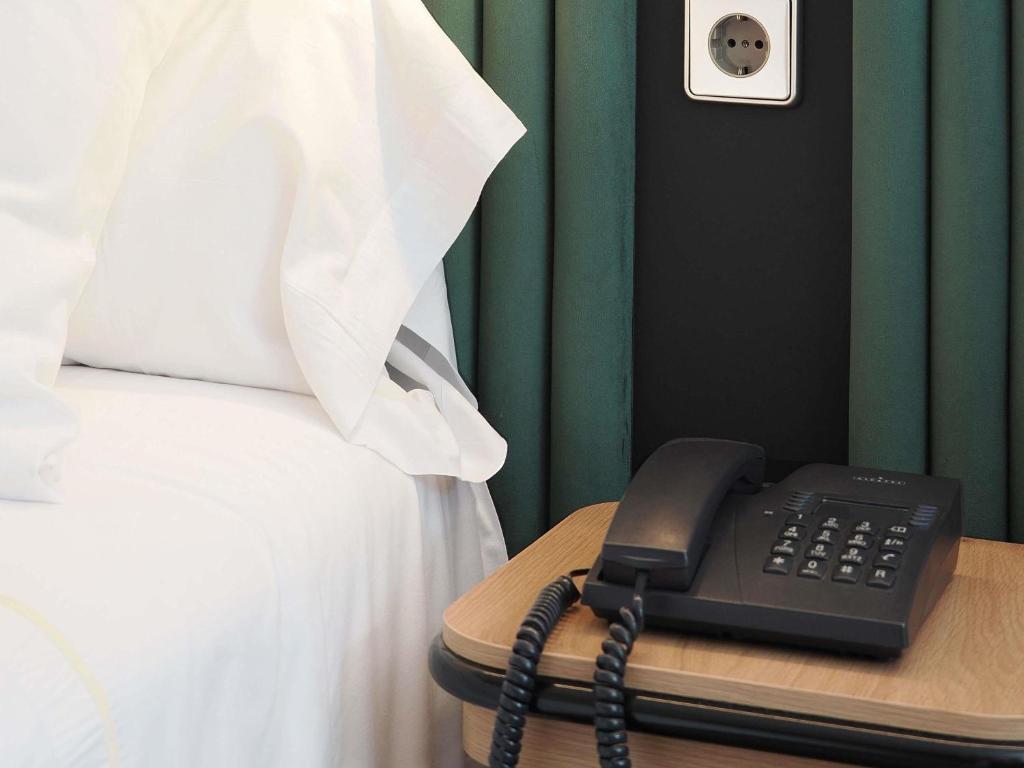 a telephone sitting on a table next to a bed at Novotel Andorra in Andorra la Vella