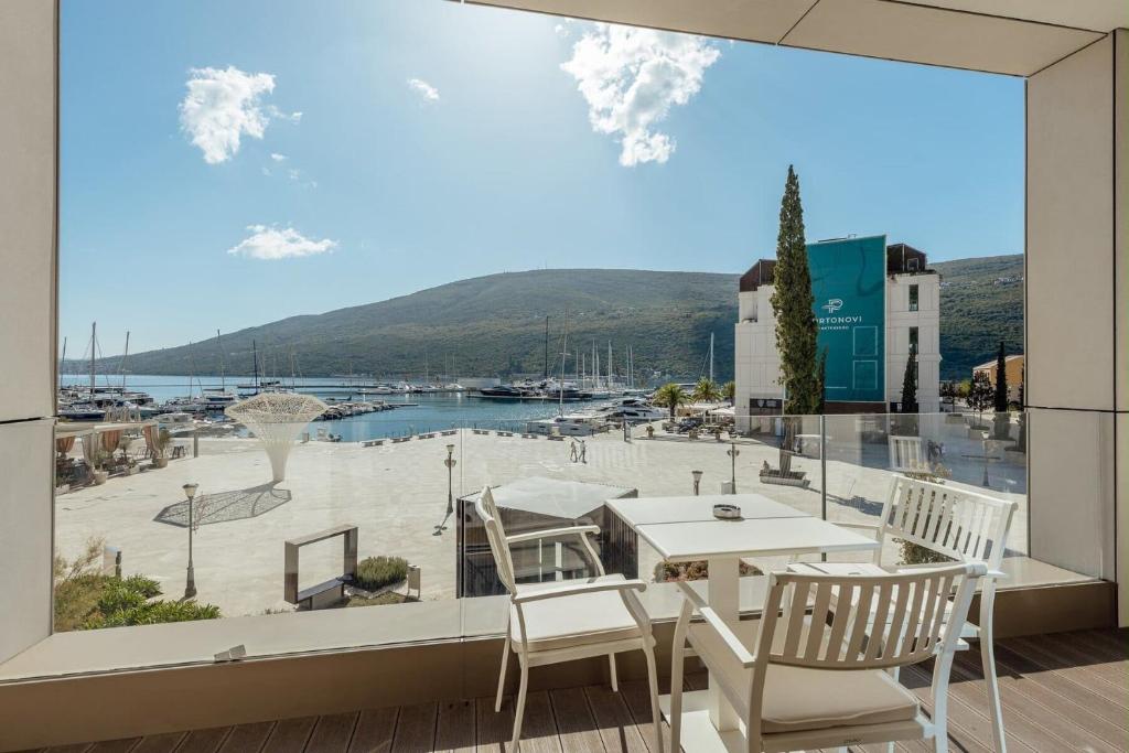 a balcony with a table and chairs and a large window at Portonovi Marina in Kumbor