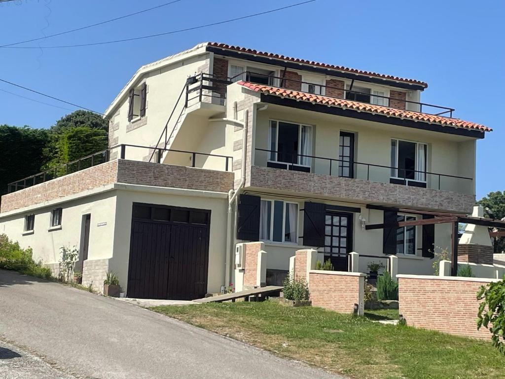a white house with a garage on a street at CASA LAS OLAS DE LANGRE in Langre