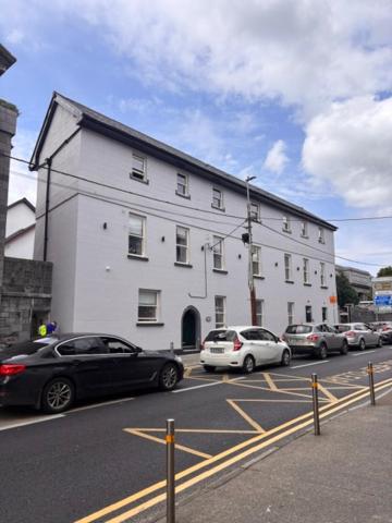 a large white building with cars parked in a parking lot at The Gate House in Galway