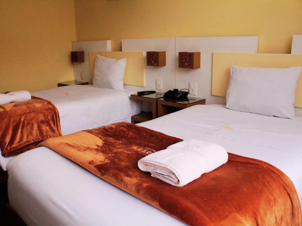 a hotel room with two beds with towels on them at Kaaro Hotel Puno in Puno