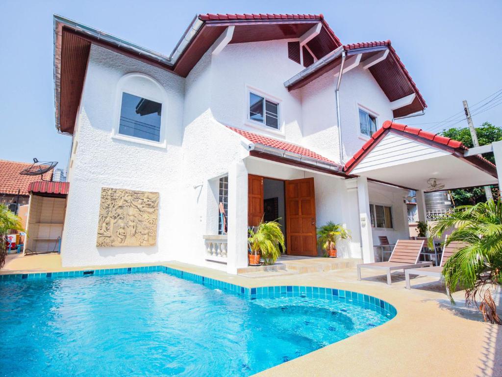 a villa with a swimming pool in front of a house at Naklua Pool Villa by Pattaya Sunny Rentals in North Pattaya