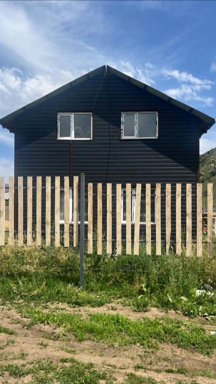 a black house behind a wooden fence at Kolsay Camp House in Kurmenty